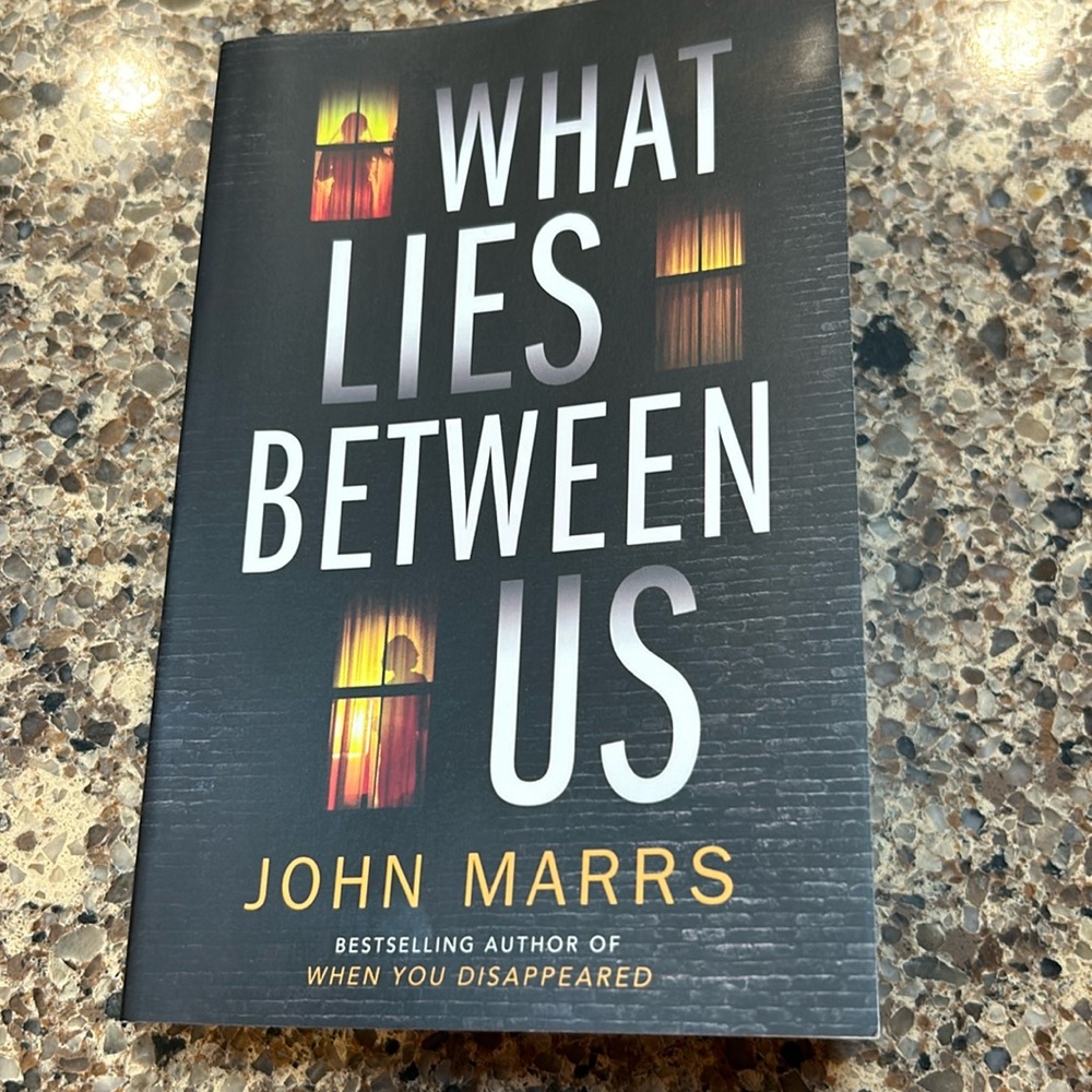 Paperback book What lies between us by John Marrs.